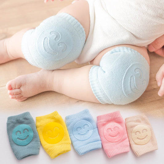 Baby wearing blue smiley crawling knee pads, with all five colours